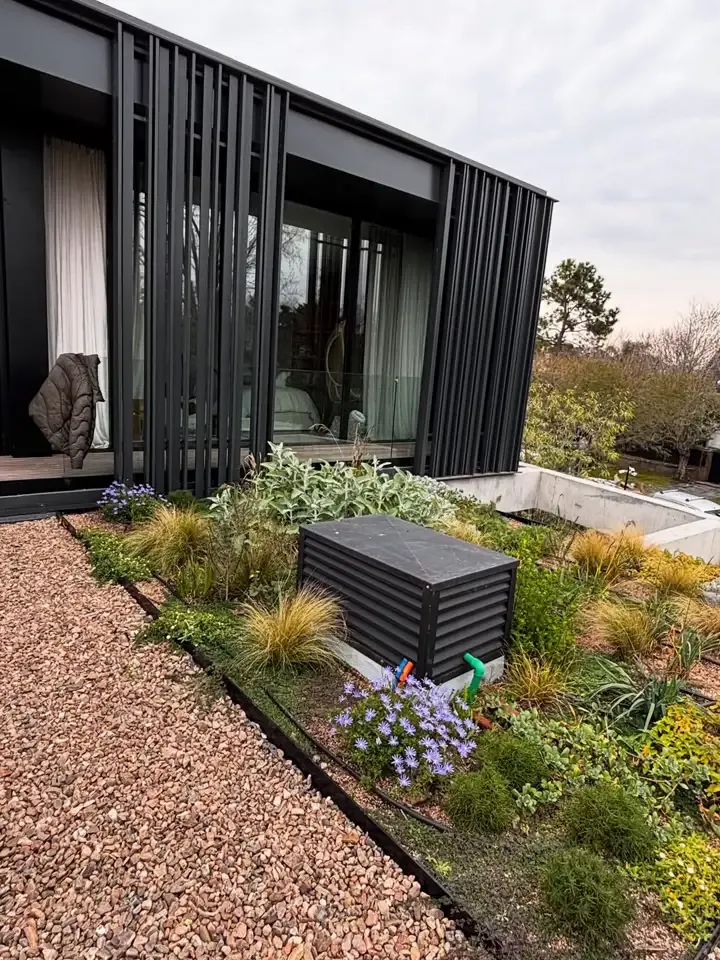 Jardín con gramíneas frente a una casa negra